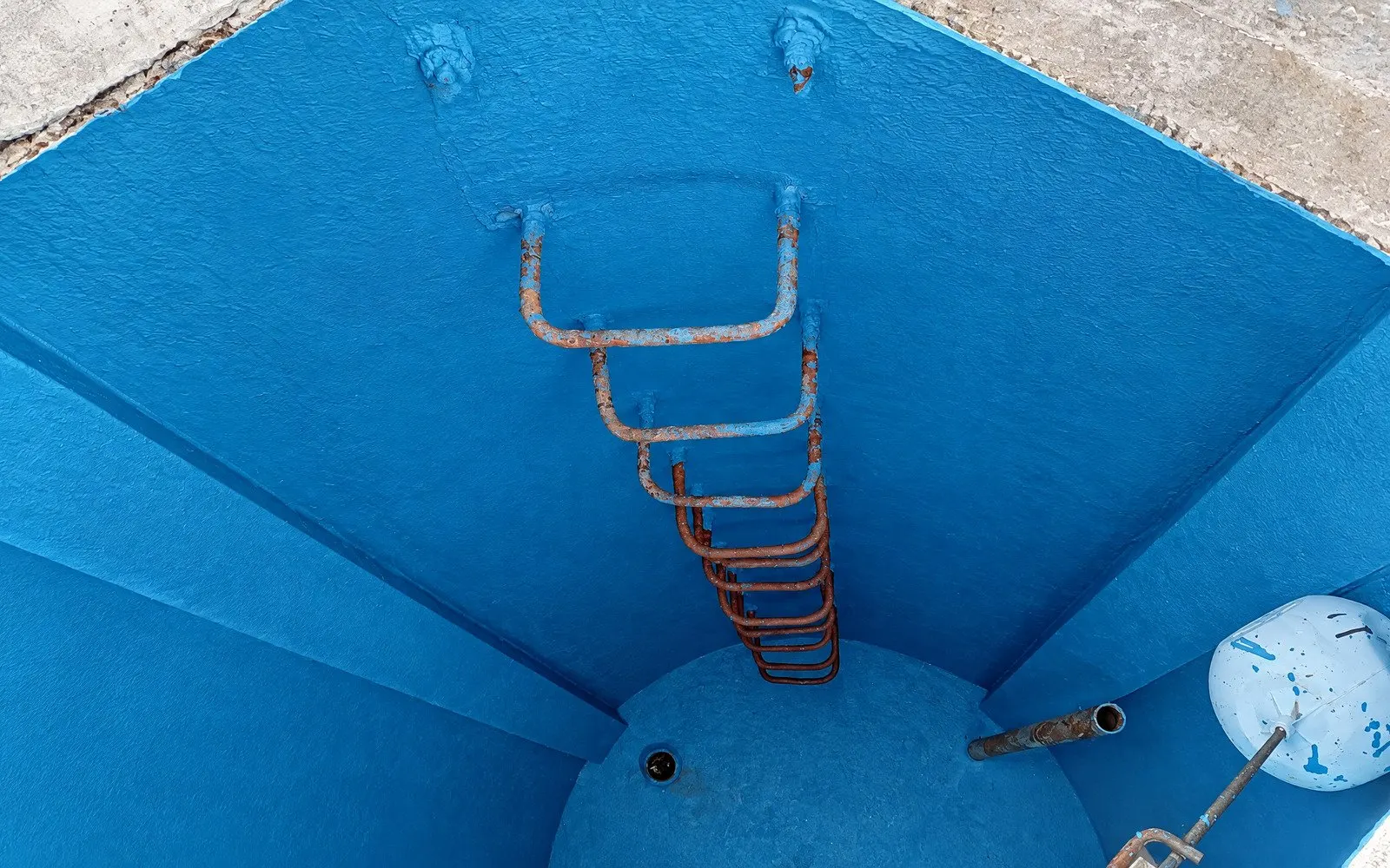 Interior de caixa d’água com revestimento impermeabilizante azul e escada de acesso