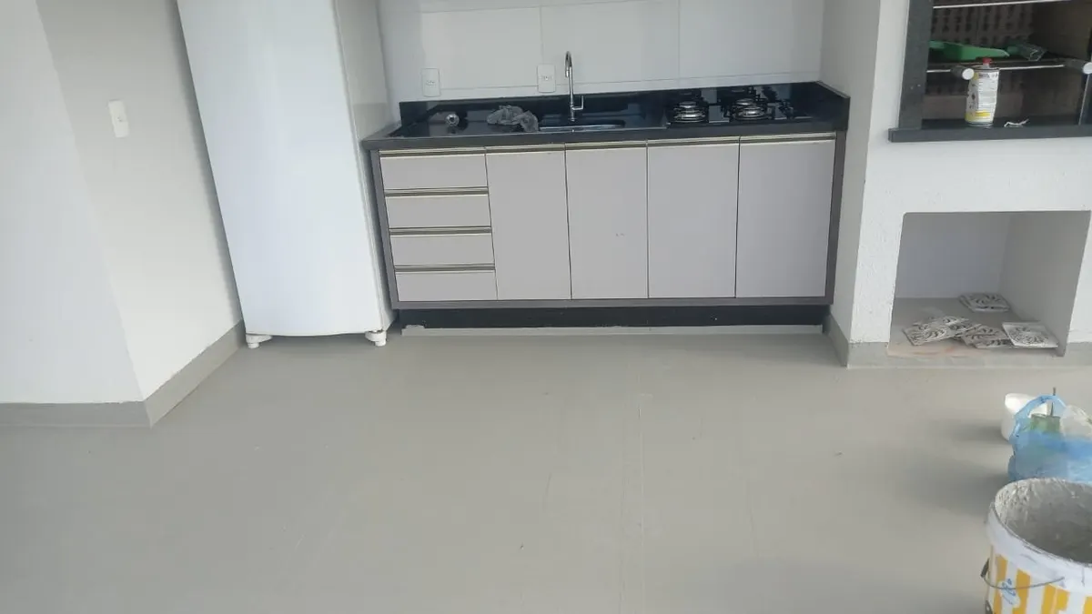 Área gourmet com piso impermeabilizado contínuo sobre base existente — pia, cooktop e armários