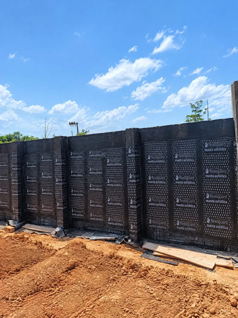 Painel contínuo de manta asfáltica Flexoguard em muro de contenção sob céu limpo