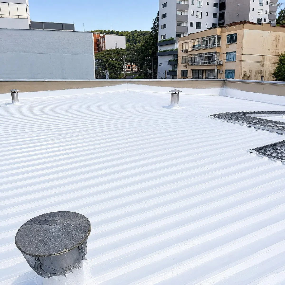 Cobertura urbana com membrana refletiva, exaustores e grades de proteção