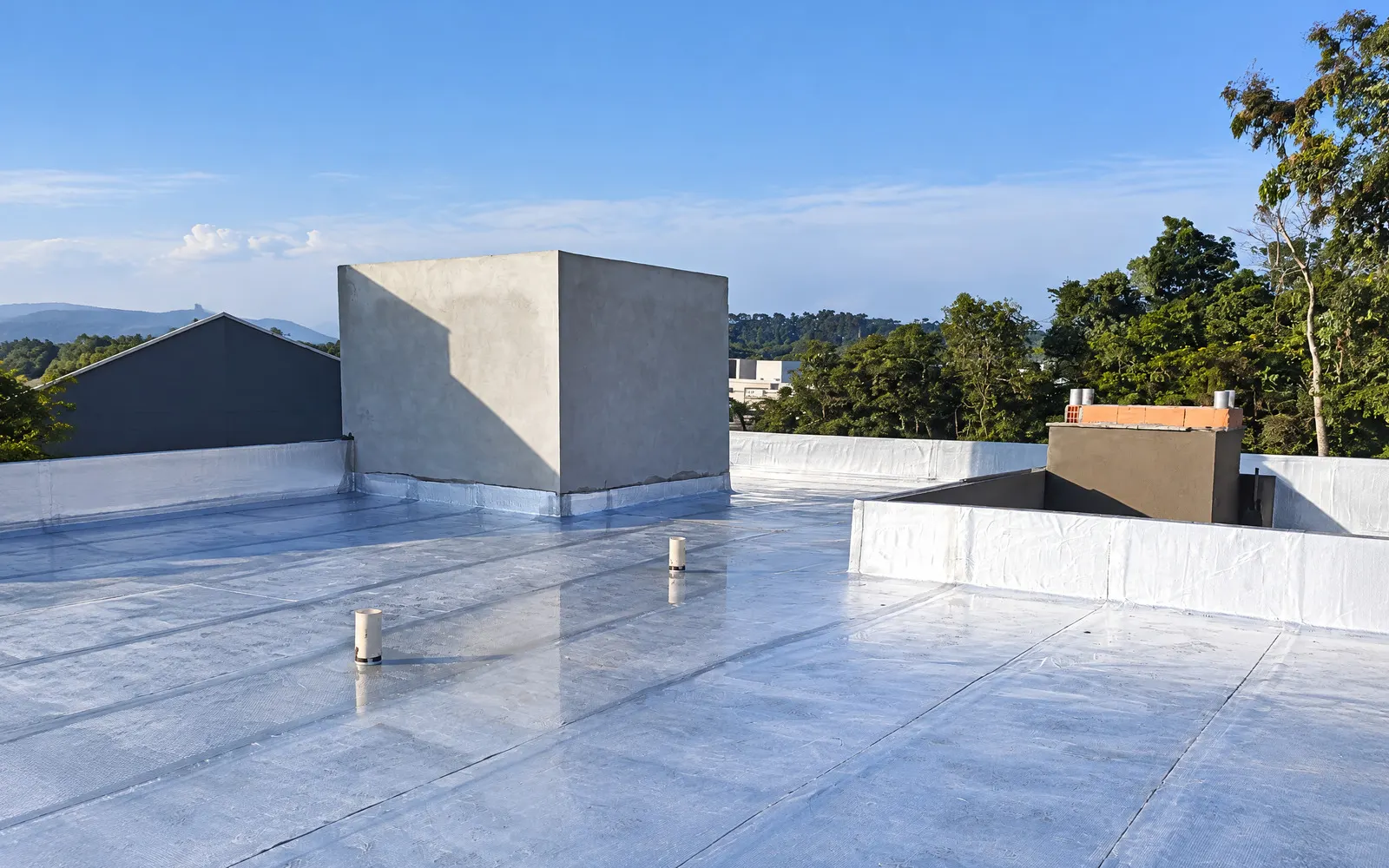 Cobertura com manta aluminizada refletindo o sol, caixas d’água e arremates perimetrais
